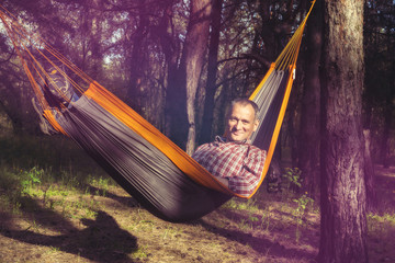 Happy man relaxes,  lying in a hammock