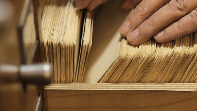 man searches something in card catalog