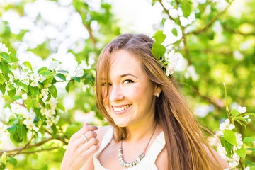 Romantic young woman in the spring garden among apple blossom, soft focus