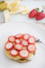 Stack of golden pancakes with strawberries, banana,