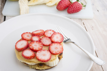 Stack of golden pancakes with strawberries, banana,