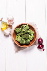 Bunch of fresh green broccoli on brown plate over wooden background