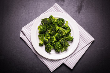 Bunch of fresh green broccoli on brown plate over wooden background