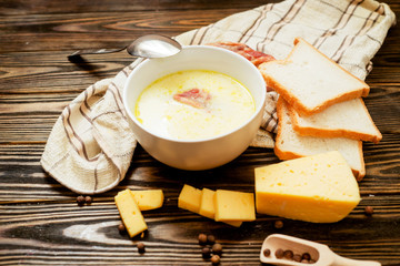 
cheese soup with smoked pork ribs , potatoes, carrots , peppers , spices and bread on the wooden background