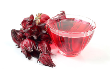 Roselle fruits against a cup of Roselle tea on white background.