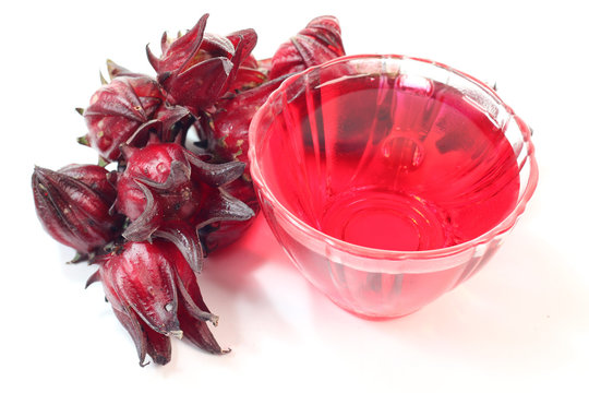 Roselle fruits against a cup of Roselle tea on white background.
