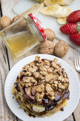 Pancakes with banana , walnut & chocolate on wood background