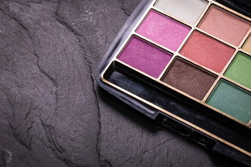 Various makeup products on dark background with copyspace