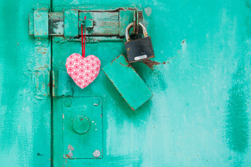 red heart is hanging on a door with lock