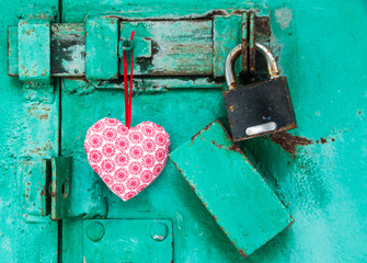 red heart is hanging on a door with lock