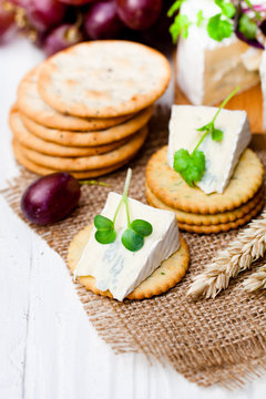 Crackers and  wedge of blue camembert cheese on sackcloth napkin