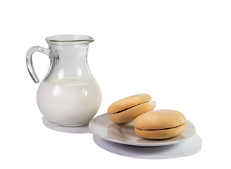 Glass jug with milk and cookies on a plate.