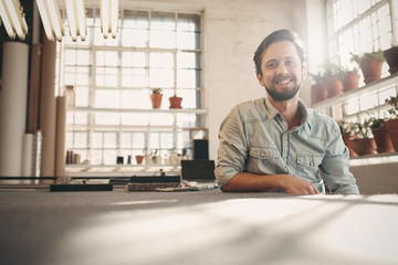 Designer entrepeneur looking relaxed in his studio with sunflare