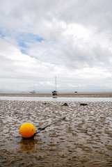 An orange buoy on a beach in Abersoch at low tide