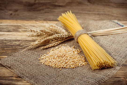 a bandle of spagetti with wheat stack on stackcloth and wooden rustic background