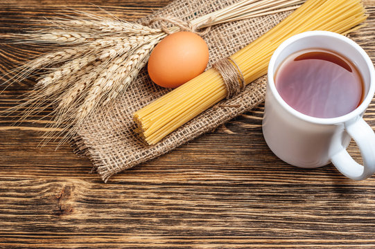 a bandle of spagetti with cup of tea, wheat stack on stackcloth and wooden rustic background
