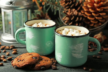Two mugs of hot cacao with marshmallow and cookies on black table