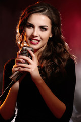 Portrait of beautiful singing woman on red background, close up