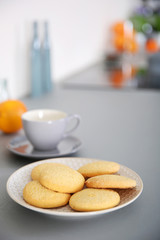 Cup of coffee and plate of cookies on the table against unfocused background