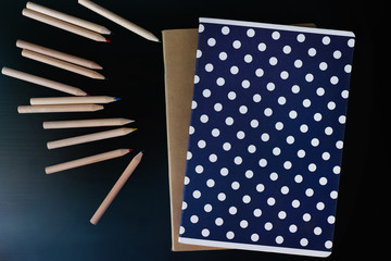 Notebooks with coloured pencils on black table