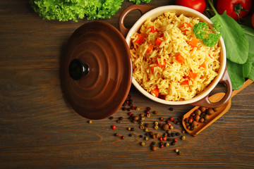 Pan of vegetarian rice with vegetables and allspice on wooden table, top view