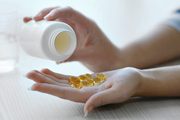 Woman spills yellow medical capsules  to her hand, close up