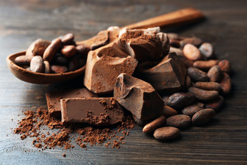 Spoon with aromatic cocoa and chocolate on wooden background, close up