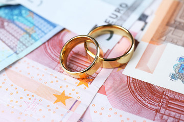 Golden wedding rings on euro banknotes background. Marriage of convenience