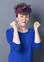 success concept - frowning 30s woman with retro hairstyle smiling with arms raised for shy competition,studio shot.