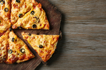Delicious sliced pizza on wooden board, close up
