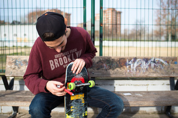 Man sitting on a Bench while reparing his Skate © harodominguez
