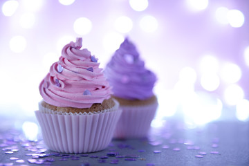 Two cupcakes on a glitter background, close up