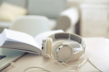 Obraz na płótnie Canvas Headphones and book on white table against defocused background