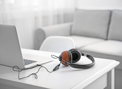 Headphones And Laptop On White Table Against Defocused Background