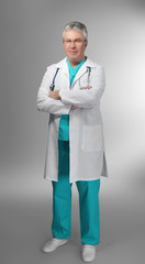 A handsome doctor with crossed arms standing on grey background
