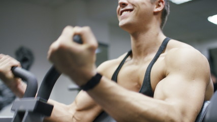 Attractive young man doing bicep curls on a machine in the gym