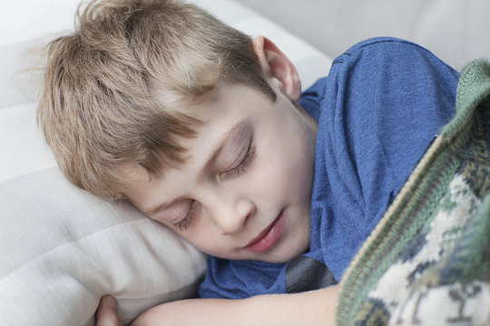 Little Boy Sleeping On Sofa In Room