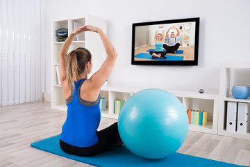 Fototapeta na wymiar Pregnant Woman Doing Yoga By Watching Television