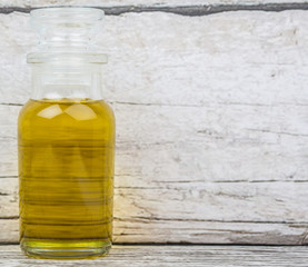 Olive oil in glass bottle over wooden background