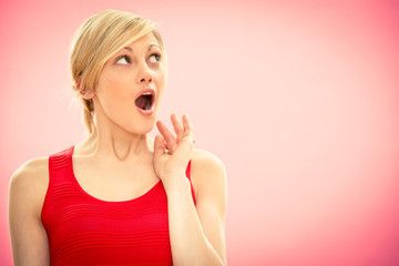 Young beautiful woman in red dress surprised on pink