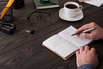 Male writes in a diary on the office desktop