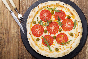 Pizza vegetarian on plate on stone black try with fresh tomatoes