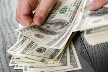 young female hands count dollar bills on wood table