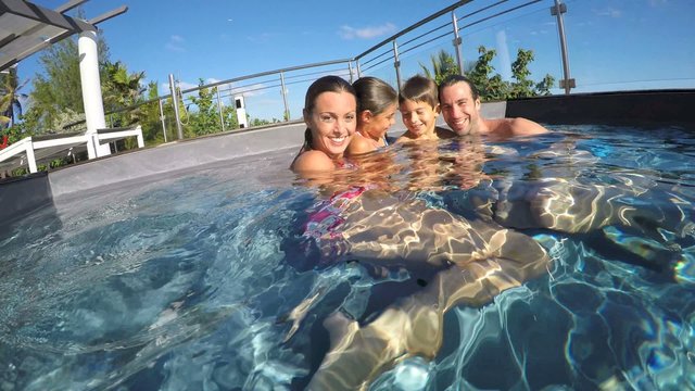 Happy family in swimming-pool, summertime