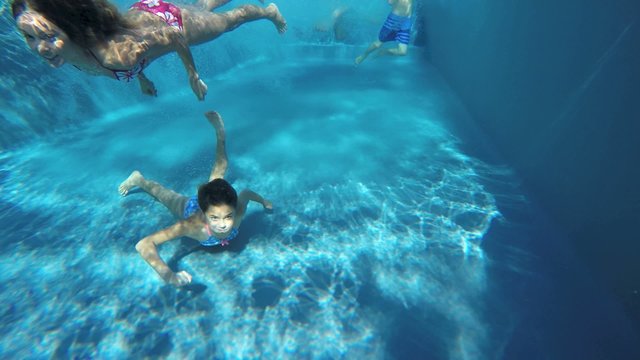 Family jumping into pool and swimming underwater