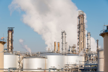 oil refinery with smoking chimneys against blue sky