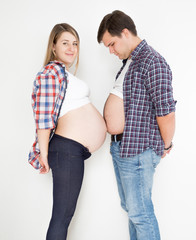 portrait of pregnant woman and husband touching with big tummies