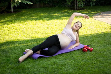 Expectant mother stretching before yoga on grass at park