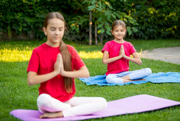 Two cute girls practicing yoga at park at sunny day