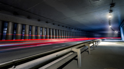 Obraz premium Tunnel under bridge at night with cars rushing